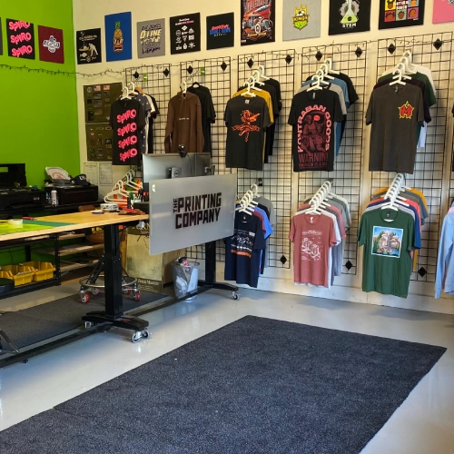 The Printing Company store with custom printed t-shirts on the wall