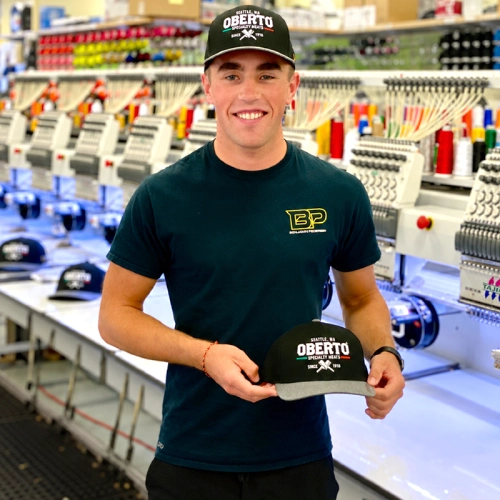 Customer holding an embroidered cap by the embroidery machines