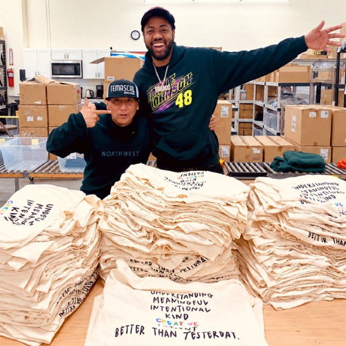 Two customers with stacks of custom printed t-shirts